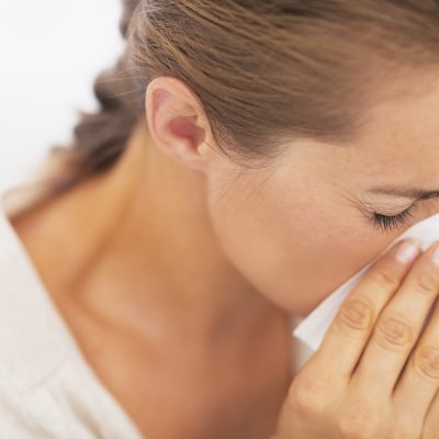 Woman blowing nose into handkerchief